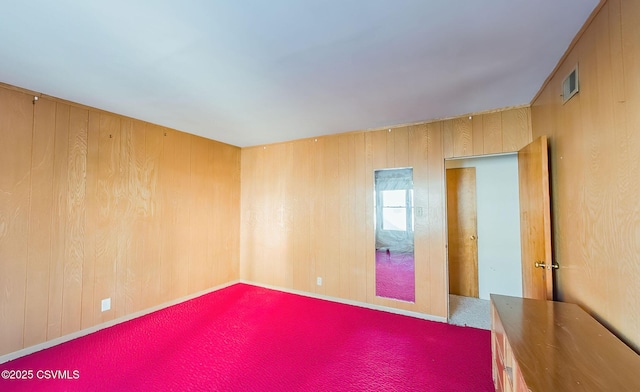 carpeted empty room with wooden walls