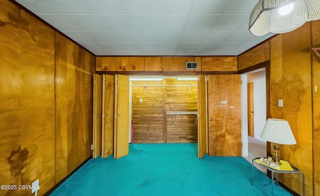 carpeted spare room with wood walls