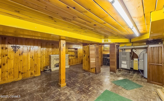 basement with wooden walls, wooden ceiling, and water heater