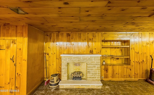 unfurnished living room with wood ceiling, wooden walls, and a stone fireplace