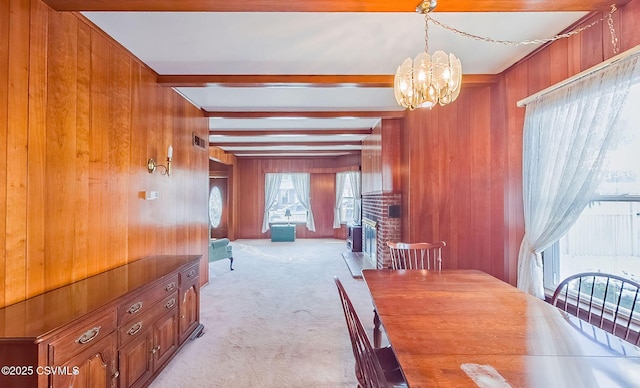 carpeted dining area with an inviting chandelier, wooden walls, beam ceiling, and a fireplace