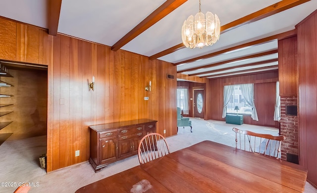 dining space with beamed ceiling, wooden walls, light carpet, and a notable chandelier