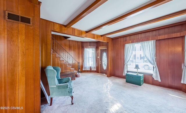 sitting room with light carpet, beam ceiling, and wood walls