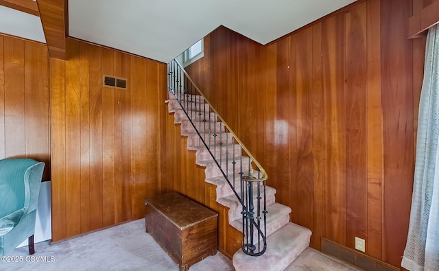 stairway with carpet floors and wood walls