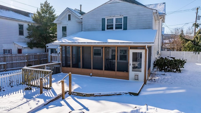 snow covered property featuring a sunroom