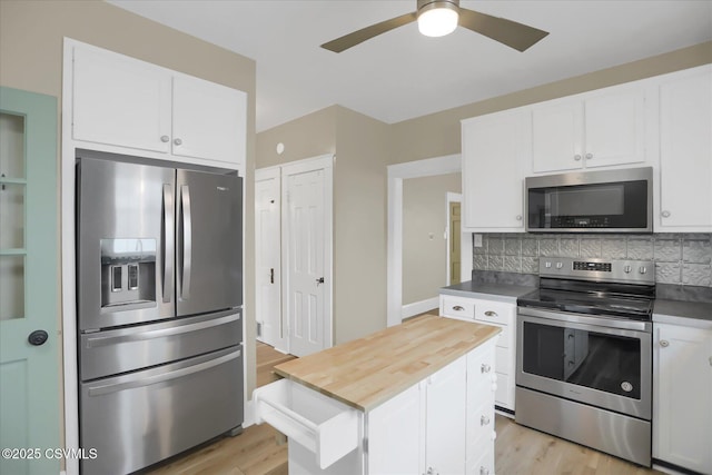 kitchen with appliances with stainless steel finishes, white cabinetry, decorative backsplash, a center island, and light hardwood / wood-style floors