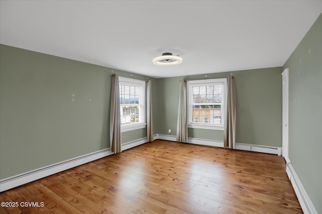 empty room with light hardwood / wood-style floors, a healthy amount of sunlight, and baseboard heating