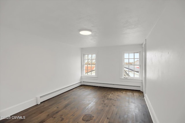 empty room featuring dark hardwood / wood-style floors and a baseboard heating unit