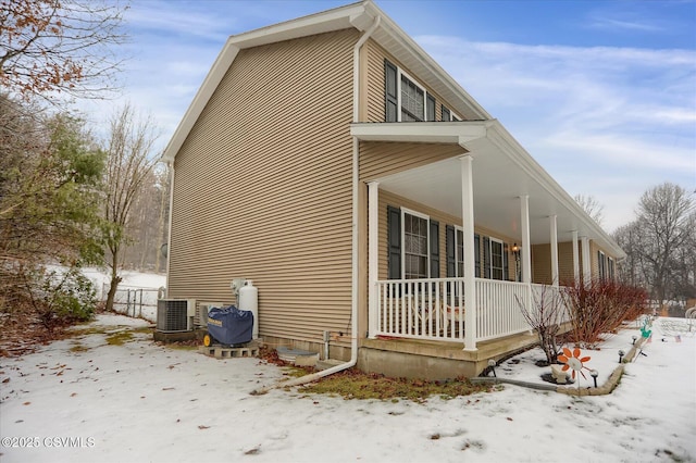 snow covered property featuring central AC and covered porch