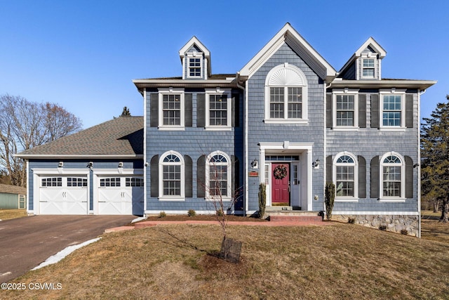 colonial inspired home featuring a garage and a front lawn