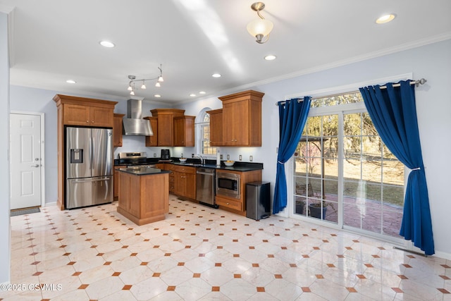 kitchen with ornamental molding, stainless steel appliances, wall chimney exhaust hood, and a kitchen island