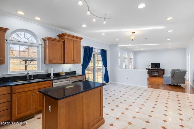 kitchen featuring crown molding, a center island, sink, and a healthy amount of sunlight