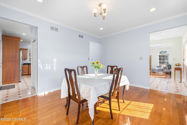 dining room featuring ornamental molding, a notable chandelier, and light wood-type flooring