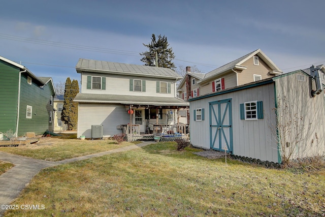 view of front facade featuring a porch, a front yard, central AC unit, and a storage shed