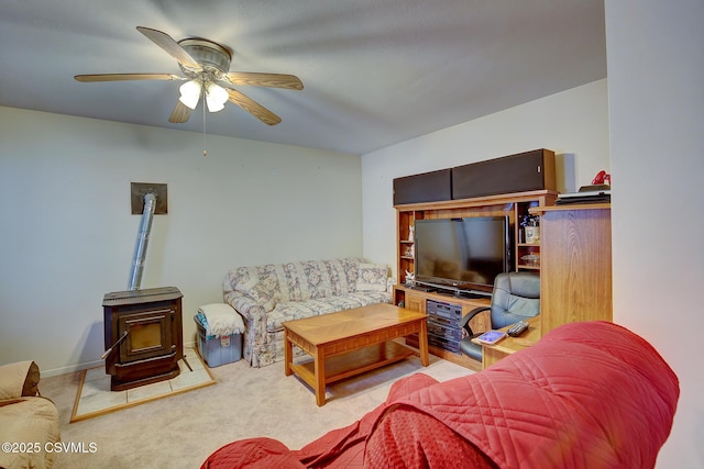 carpeted living room featuring a wood stove and ceiling fan