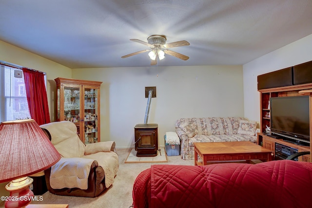 carpeted living room featuring a wood stove and ceiling fan