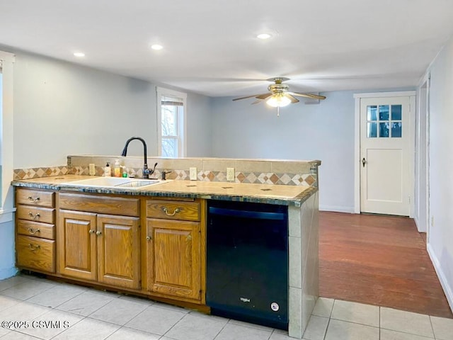 kitchen with sink, light tile patterned floors, dishwasher, kitchen peninsula, and ceiling fan