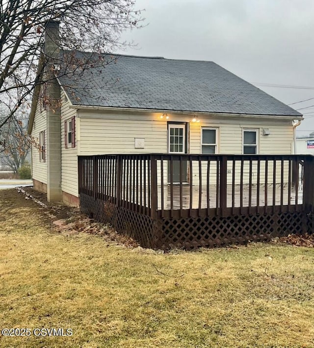 rear view of property with a wooden deck and a lawn