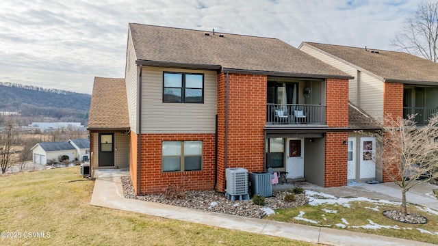 back of property featuring a balcony, cooling unit, and a lawn