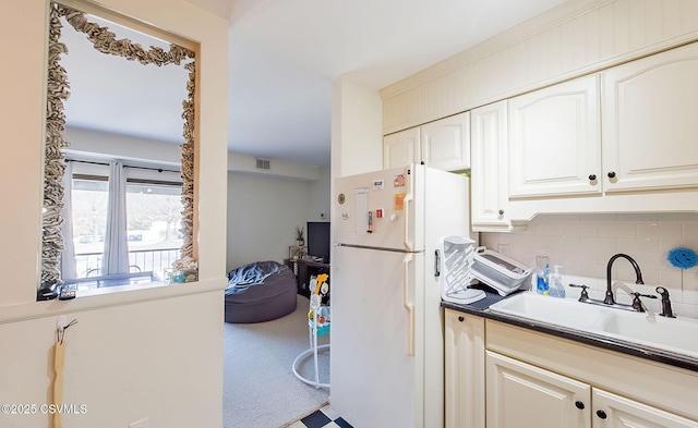 kitchen featuring tasteful backsplash, sink, carpet, and white fridge