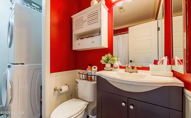 bathroom featuring vanity, toilet, and stacked washing maching and dryer