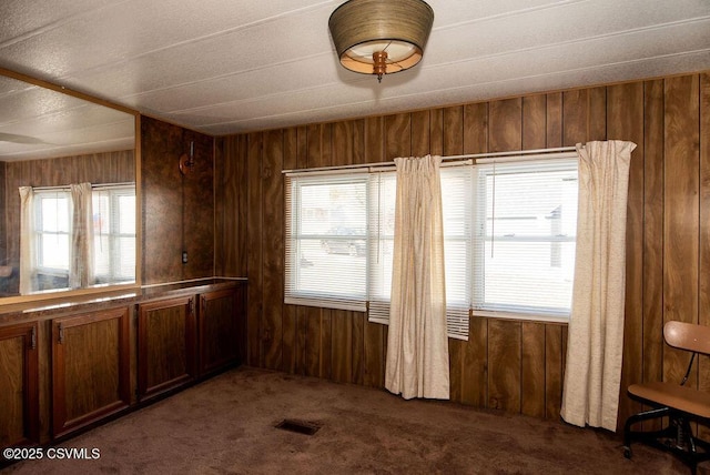 unfurnished dining area with dark carpet and wood walls