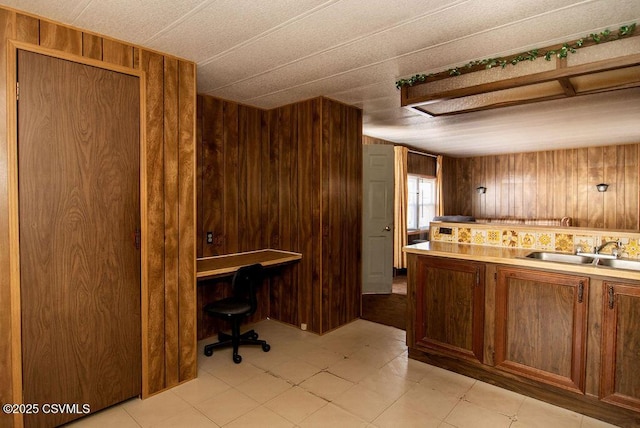 kitchen featuring wooden walls and sink