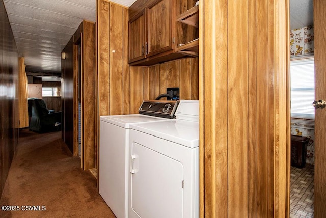 laundry area with cabinets, wooden walls, washer and clothes dryer, and carpet