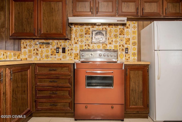 kitchen featuring stove, white fridge, and decorative backsplash