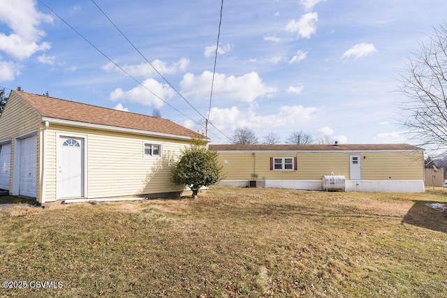 rear view of house featuring a garage, central AC unit, and a lawn