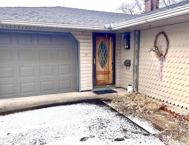 snow covered property entrance with a garage