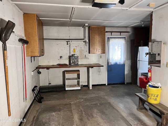 interior space featuring white fridge, a garage door opener, and a workshop area