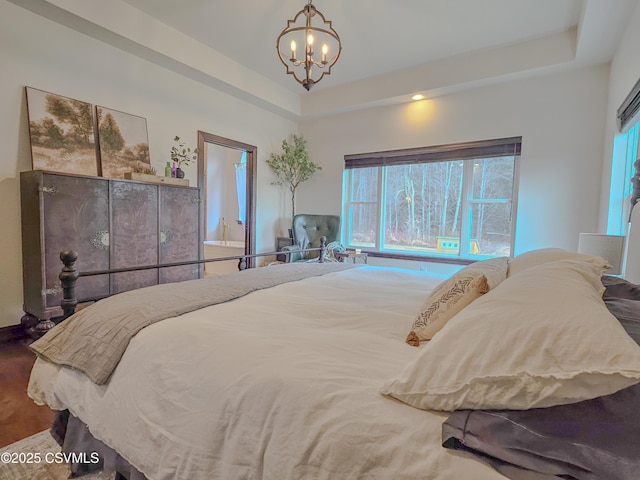 bedroom with a tray ceiling, a notable chandelier, and hardwood / wood-style flooring