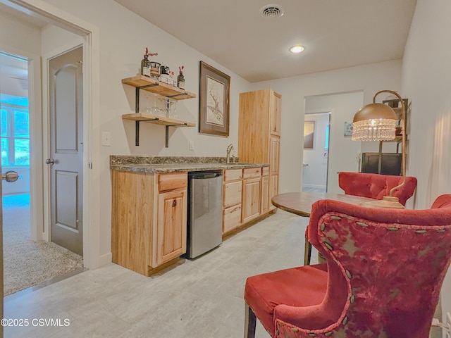 bar with light brown cabinetry, sink, and dishwasher