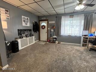 interior space with a paneled ceiling, ceiling fan, and carpet