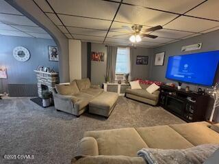 living room featuring ceiling fan, a fireplace, and a drop ceiling