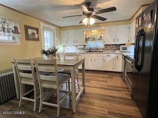 kitchen with radiator, hardwood / wood-style flooring, sink, white cabinets, and black fridge