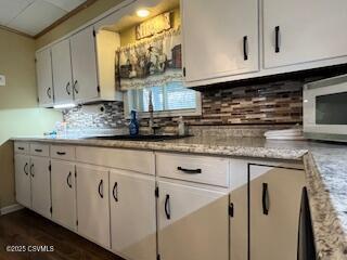 kitchen featuring sink, light stone counters, white cabinets, and backsplash