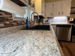 kitchen with sink, dark hardwood / wood-style flooring, decorative backsplash, light stone counters, and stainless steel appliances