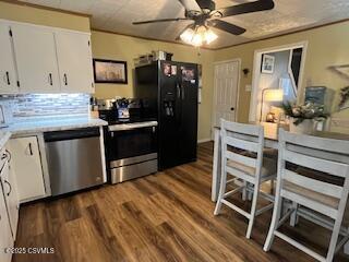 kitchen featuring ceiling fan, appliances with stainless steel finishes, dark hardwood / wood-style flooring, and white cabinets