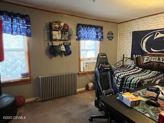 bedroom with cooling unit, radiator heating unit, brick wall, and carpet