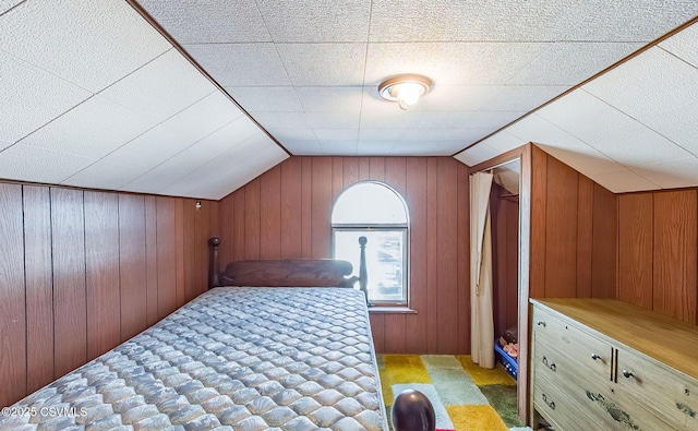 carpeted bedroom featuring wooden walls and vaulted ceiling