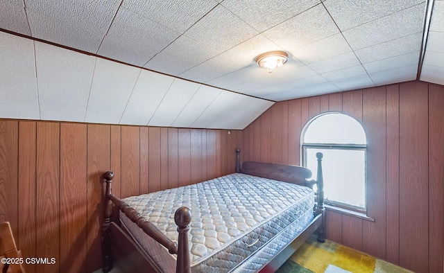 unfurnished bedroom with vaulted ceiling and wooden walls