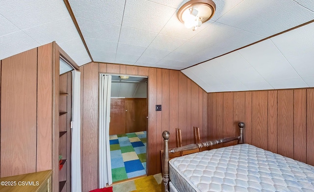 bedroom featuring lofted ceiling and wooden walls