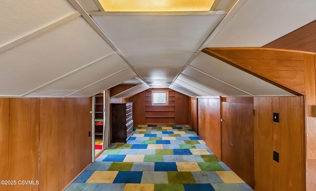 bonus room featuring lofted ceiling and wood walls