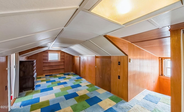 bonus room featuring vaulted ceiling and wood walls