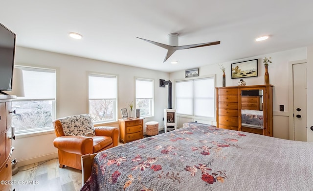 bedroom with ceiling fan, light hardwood / wood-style floors, and multiple windows