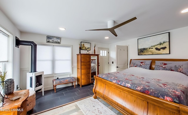 bedroom featuring a wood stove, dark wood-type flooring, and ceiling fan