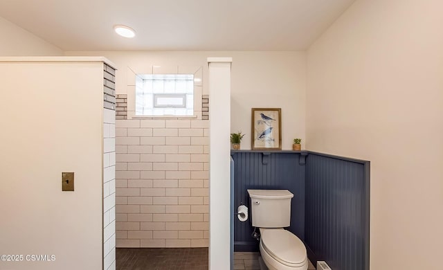 bathroom with a tile shower and toilet