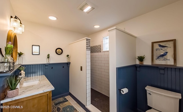 bathroom with tile patterned floors, vanity, toilet, and a tile shower